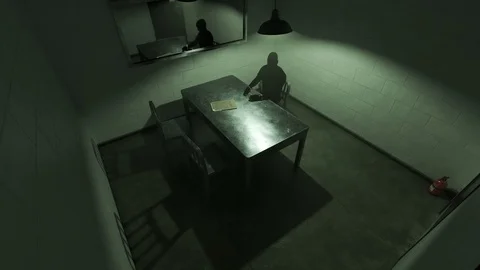 Dark silhouette of a man sitting in empty interrogation room. Video stock 89586487
