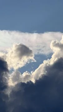 Dark silhouette of storm clouds opening up to reveal bright, glowing white Stock Photos