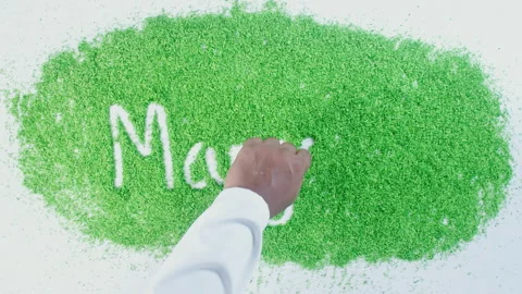 Dark skin man's hand writing in green sand words Marjoram Stock Footage 248645484