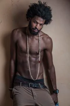 A dark-skinned, curly-haired guy with an athletic build , wearing long beads and Stock Photos