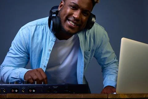 Dark-skinned DJ poses in front of the camera. Headphones off, face smile Stock Photos