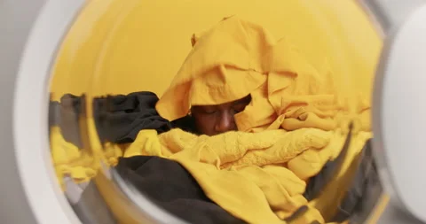 Dark skinned ethnic man poses from inside of washer being fully covered with Stock Footage 157335024