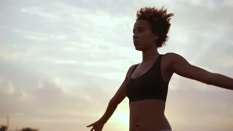 Dark skinned girl with afro hairstyle raises hands then lowers them and folds Stock Footage