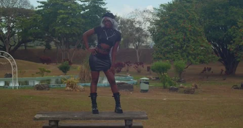 A dark-skinned girl wearing a sharp leather outfit and boots as she walks Stockbeeldmateriaal 336649976