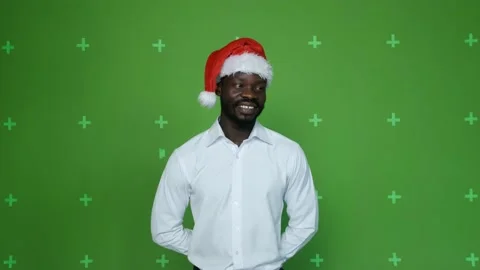 Dark-skinned guy in a Christmas hat gives gifts to the camera. Stock Footage 130830745