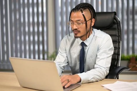 A dark-skinned guy with an interesting and original image works at the comput Stock Photos
