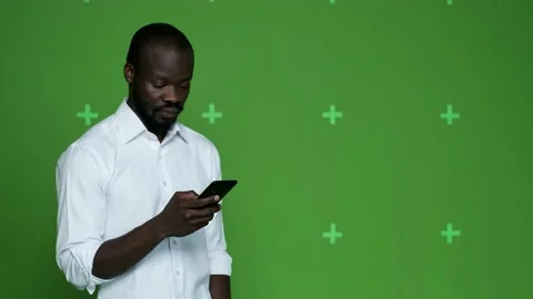 Dark-skinned guy looks at the mobile phone and shows different emotions Stock Footage 130831150