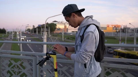 Dark-skinned guy share electric scooter on the bridge above car road Stock Footage 115753570