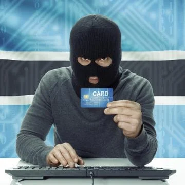 Dark-skinned hacker with flag on background holding credit card - Botswana 写真素材