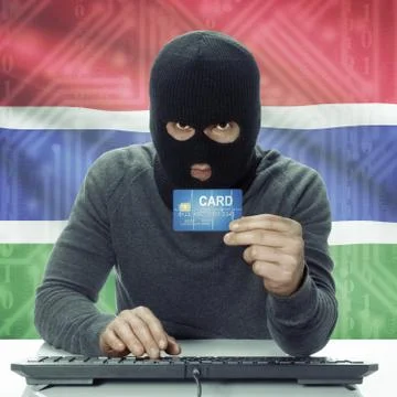 Dark-skinned hacker with flag on background holding credit card - Gambia 写真素材