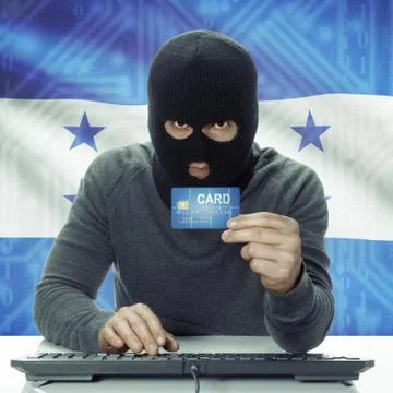 Dark-skinned hacker with flag on background holding credit card - Honduras Фото