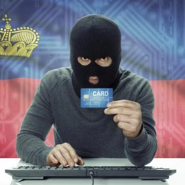 Dark-skinned hacker with flag on background holding credit card - Liechtenste Stock Photos