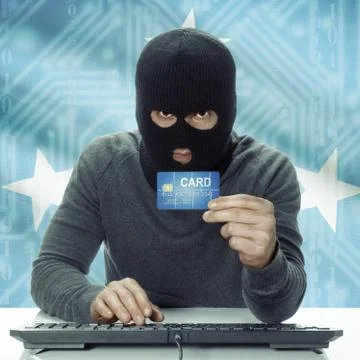 Dark-skinned hacker with flag on background holding credit card - Micronesia 스톡 사진
