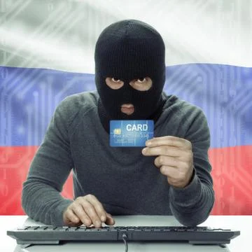 Dark-skinned hacker with flag on background holding credit card - Russia 写真素材