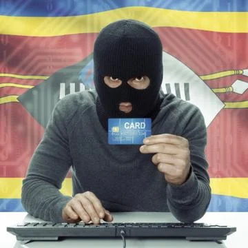 Dark-skinned hacker with flag on background holding credit card - Swaziland 写真素材