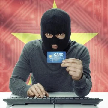 Dark-skinned hacker with flag on background holding credit card - Vietnam 写真素材
