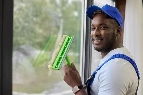 Dark-skinned handsome guy working with a brush in his hand to wash windows Foto stock