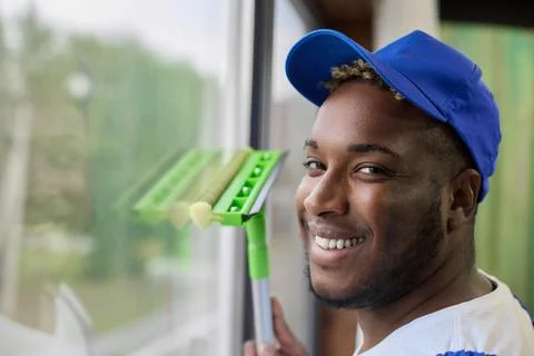 Dark-skinned handsome guy working with a brush in his hand to wash windows Stock Photos