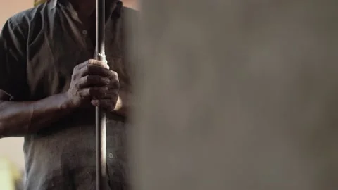 A dark skinned Indian worker holding a metal pole in his hands for manual labor. Stock Footage 144660733