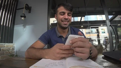 Dark Skinned Man Looking At His Phone In Cafe And Smiling Stock Footage 93980869