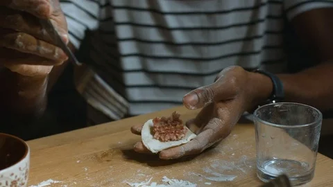 Dark skinned man puts meat in dough for dumpligs Stock Footage 83852913