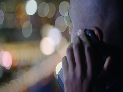 Dark skinned man talks on phone while looking out over LA city lights 4K Stock Footage 73100876