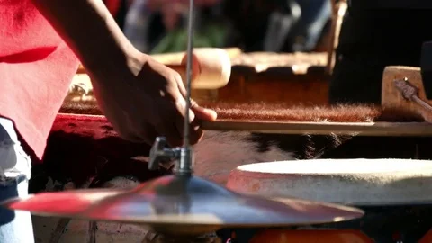 Dark skinned man's hands holding drum sticks hitting animal hair covered drums  動画素材 80342297