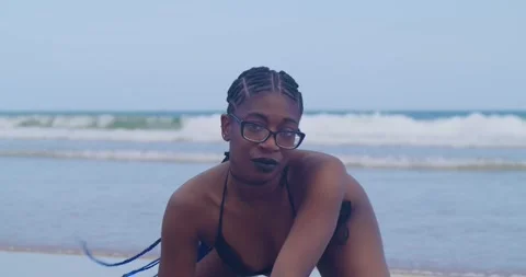 A dark-skinned model in a black bikini posing under the Caribbean sun, azure Stock Footage 335120918