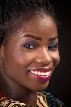 Dark skinned model with open smile showing white teeth on a black background. Stock Photos