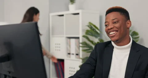 Dark-skinned office worker sits in front of computer at desk having video Stock Footage 163877722