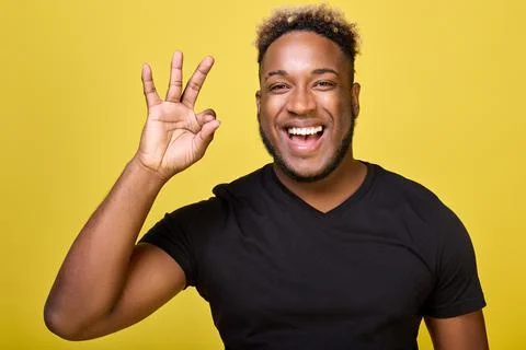 Dark-skinned smiling man makes a sign ok with his fingers Stock Photos