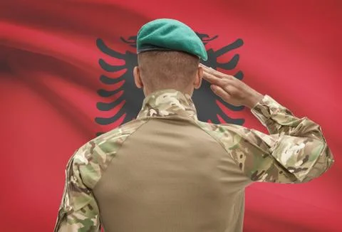 Dark-skinned soldier in hat facing national flag series - Albania Stock Photos
