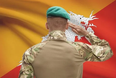Dark-skinned soldier in hat facing national flag series - Bhutan 스톡 사진