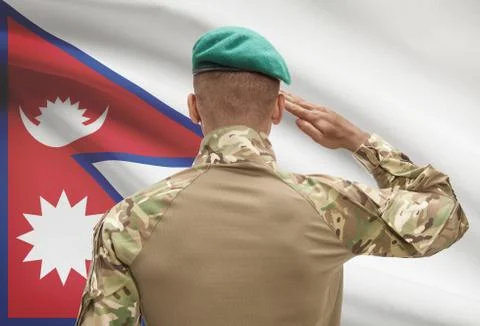 Dark-skinned soldier in hat facing national flag series - Nepal 스톡 사진