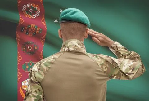 Dark-skinned soldier in hat facing national flag series - Turkmenistan Fotos de archivo