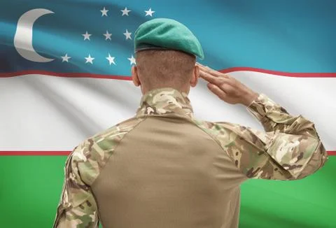 Dark-skinned soldier in hat facing national flag series - Uzbekistan Stock Photos