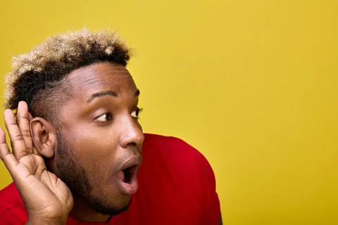 A dark-skinned surprised guy leaned forward leaning his hand against his ear Stock Photos