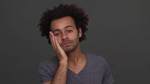 Dark skinned young man with afro haircut trying to wake himself up slapping on Stock Footage 79544743