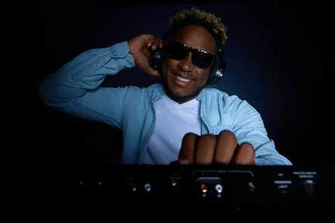 Dark skinned young man plays music in club on gray background Stock Photos