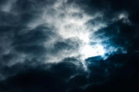 A dark sky with a bird flying in the background Stock Photos