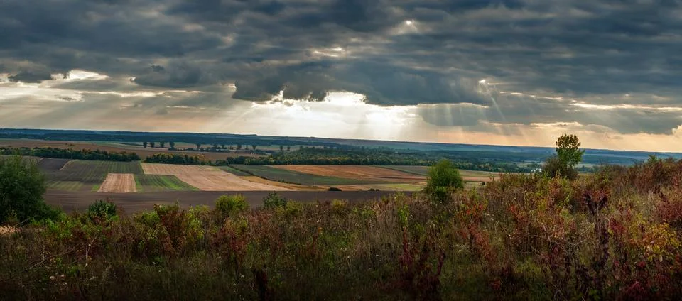 A dark sky with dramatic sun rays at Autumn landscape Stock Photos