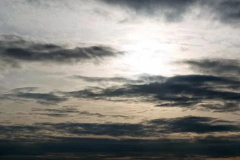 The dark sky, the evening sun, the clouds in a line along the horizon. Stock Photos