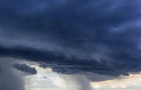The dark sky had clouds gathered to the left and a strong storm before it rai Stock Photos