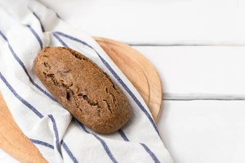 Dark sourdough einkorn bread on white wooden table with space for text. 库存照片