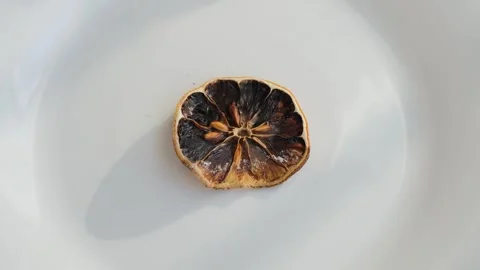 A dark, spoiled, dry piece of lemon or orange on a plate Stock-Footage 295063509