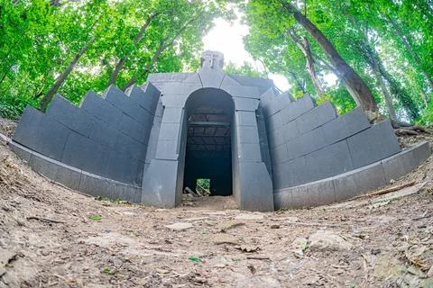 Dark-stone circular structure akin to a cave or tunnel, partially hidden in f Stock Photos