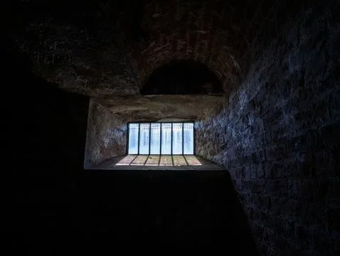 Dark stone interior with barred window light Stock Photos