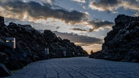 Dark stone path with person at the end heading into the sunset 스톡 사진