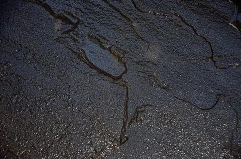 Dark stone wall shining with the light and giving the reflection wet appearan Stock Photos