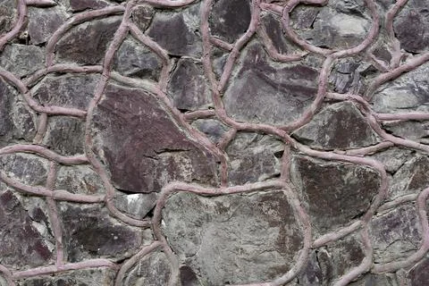 Dark stone wall texture with decorative pink mortar joints Stock Photos
